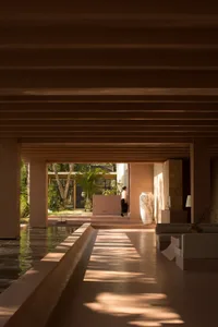 A modern lobby with a poolside view and concrete walls.