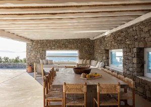 An indoor residential space with stone walls and a large dining table with chairs.