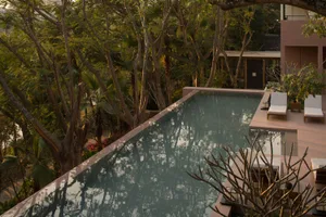 A serene modern resort swimming pool with a concrete edge and surrounding greenery.
