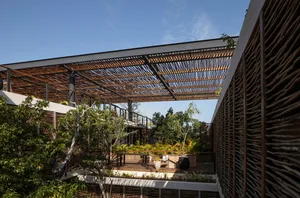 Modern rooftop space with a wooden lattice roof structure surrounded by greenery.