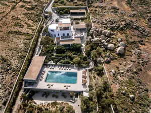 Modern white villa with surrounding natural rock formations and mature vegetation