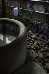 Photograph of a stone garden with bamboo and rock formations, featuring a lantern and water feature.