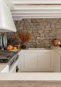 Traditional residential kitchen featuring stone walls, white plaster counter-tops, and wood accents.
