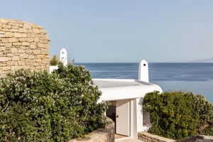 Vacation home with stone and concrete exterior and white accents overlooking the sea.