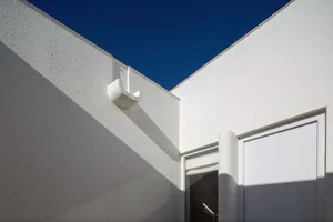 A white modern house with a corner view showing the facade and roof.