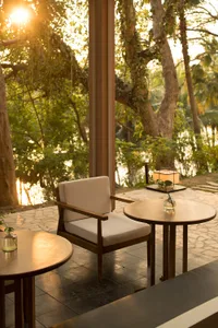 A cozy cafe featuring a wooden chair and tables with a serene outdoor view.