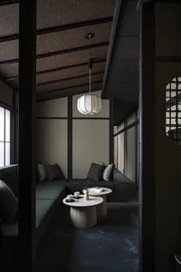 A modern minimalist living room with green furniture, concrete flooring, and wooden tables.