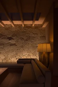 A modern interior space featuring a stone wall and a cozy seating area with a lit lamp, designed to provide comfort and style