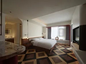 Modern bedroom featuring a cozy bed with white bedding and a unique geometric wooden floor pattern.