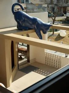 Blue cat sculpture on a concrete balcony interior.