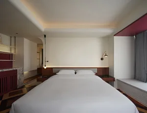 A modern bedroom featuring white walls, concrete flooring, wooden accents, and a minimalist design.