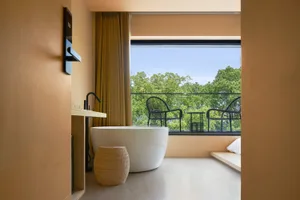 A modern minimalist bathroom featuring a ceramic bathtub and minimalist furniture.