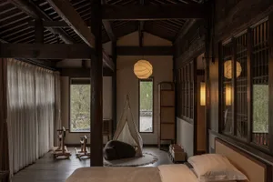 A minimalist bedroom featuring natural wood materials and a teepee tent for relaxation.