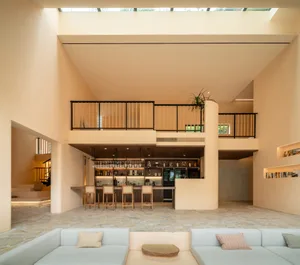 A modern minimalist living room with concrete walls and wooden accents, featuring a comfortable seating area and a bar counte