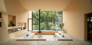 A minimalist living room with a floor-to-ceiling window, concrete walls, and a modern fireplace.