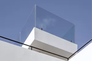 Contemporary building exterior featuring a glass balcony with white walls.