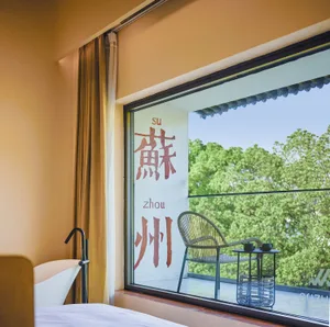 A modern hotel room featuring a glass window overlooking green trees.