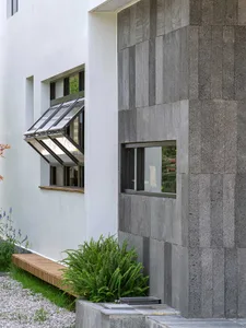 Modern house exterior featuring concrete walls, glass windows, and a wooden window box with plants.
