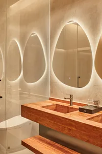 An elegant, modern marble bathroom with unique, abstract mirrors and a floating vanity.