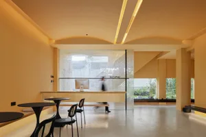 A minimalist office space with glass walls, laminate flooring, and concrete accents.