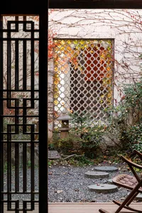 A serene garden scene featuring stone lanterns and wooden fencing, surrounded by wooden floors and stone pathways, with a ble