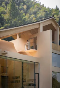 A minimalist balcony with a glass railing overlooking a forested hillside.