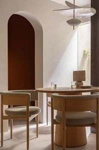 A minimalist dining room with wood furniture and light-colored cushions.
