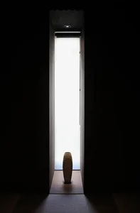 A minimalist interior design featuring a light wooden panel with a window letting in natural light.