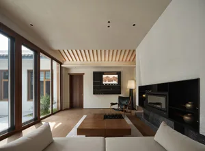 Modern minimalist living room with wooden furniture, floor-to-ceiling windows, and a cozy fireplace