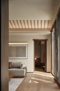 A minimalist living room featuring a comfortable seating area with a wooden sofa and pillows, complemented by a framed abstra