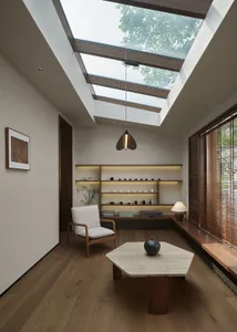 A modern living room with a large skylight, wood flooring, and a hexagonal coffee table.