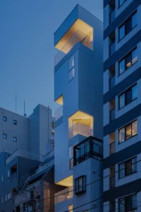 A building with blue tiled exterior, lit up during dusk
