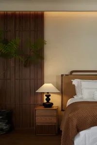 Minimalist bedroom with a wooden bed frame and nightstand, natural lighting, and greenery.