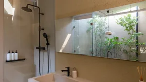 A modern bathroom featuring glass walls and concrete surfaces.