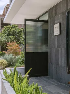 A modern building exterior featuring a black door with glass panels and a concrete facade.