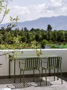 Metal outdoor furniture on a balcony overlooking a mountainous landscape.