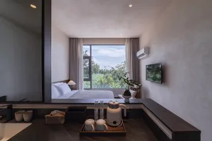 A minimalist bedroom with wooden furniture, stone accents, and glass window overlooking a natural landscape.