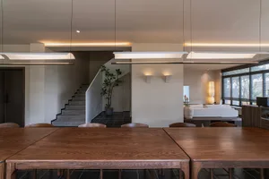 A modern residential interior with a wooden dining table and chairs, featuring contemporary furniture and minimalistic design