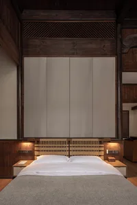 Modern minimalist bedroom featuring a wooden frame and woven headboard with white furniture, designed for relaxation and simp