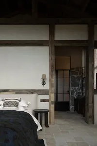Minimalist bedroom with white walls, wooden accents, and a bed with a blue and black patterned blanket.