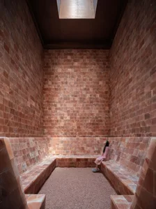 A minimalist spa room with walls lined with pink salt-rock tiles.
