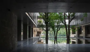 An interior space with modern design features, including concrete flooring and a large, open central area with a pool and tre
