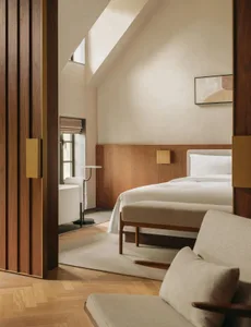 Minimalist bedroom with a white bed and wooden floor.