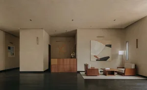 A minimalist lobby featuring concrete walls, wooden furniture, and fabric seating.
