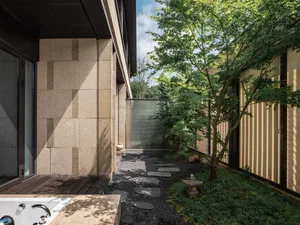 A minimalist patio featuring concrete slabs, gravel pathway, and wooden elements.