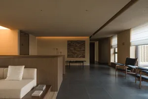 Modern residential interior featuring a sleek, minimalist design with wooden elements, dark flooring, and a cozy seating area