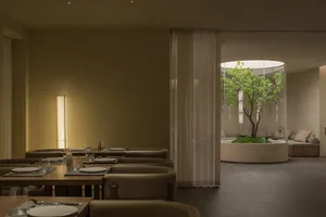 A modern restaurant interior featuring glass walls, marble tables, and contemporary lighting.