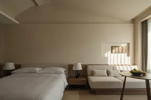A serene minimalist bedroom with a bed, couch, and a fruit bowl on a table.