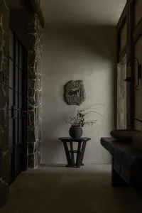Rustic interior with stone and plaster finishes, featuring a cozy living area with furniture and decorative elements.