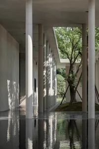 Concrete columns in a modern office setting, with a court area surrounded by greenery.